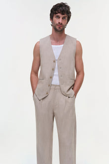 Man wearing a beige linen vest with button front over a white t-shirt, paired with matching beige trousers.