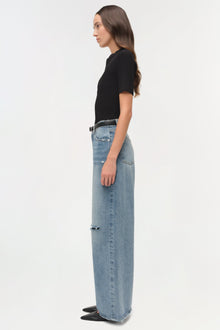 Woman wearing light blue denim straight crop pants with ripped details and a black ribbed short-sleeve top.