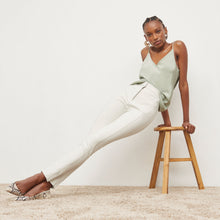 Front image of a woman standing wearing the Curie Pant—Everstretch in Bone