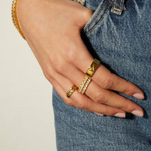 Model. Hand wearing gold rings with a denim background