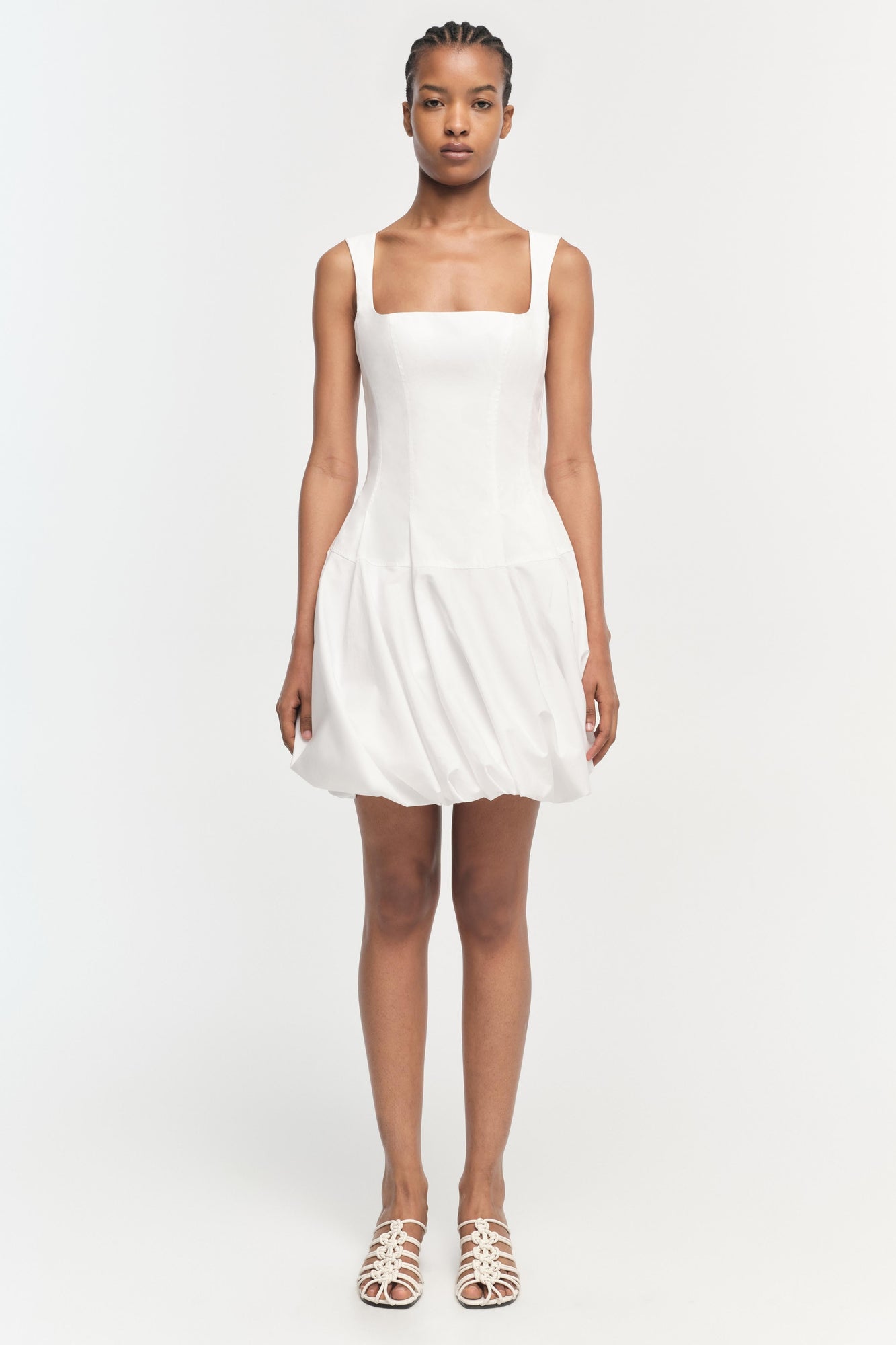 White sleeveless mini dress with square neckline and gathered skirt hem.