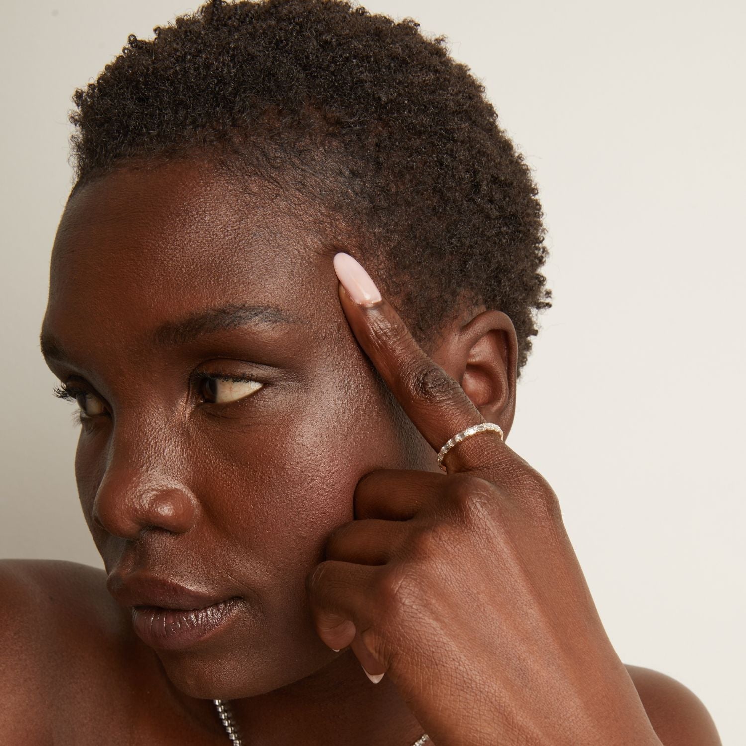 Model. Close-up of a person with their hand near their face on a neutral background