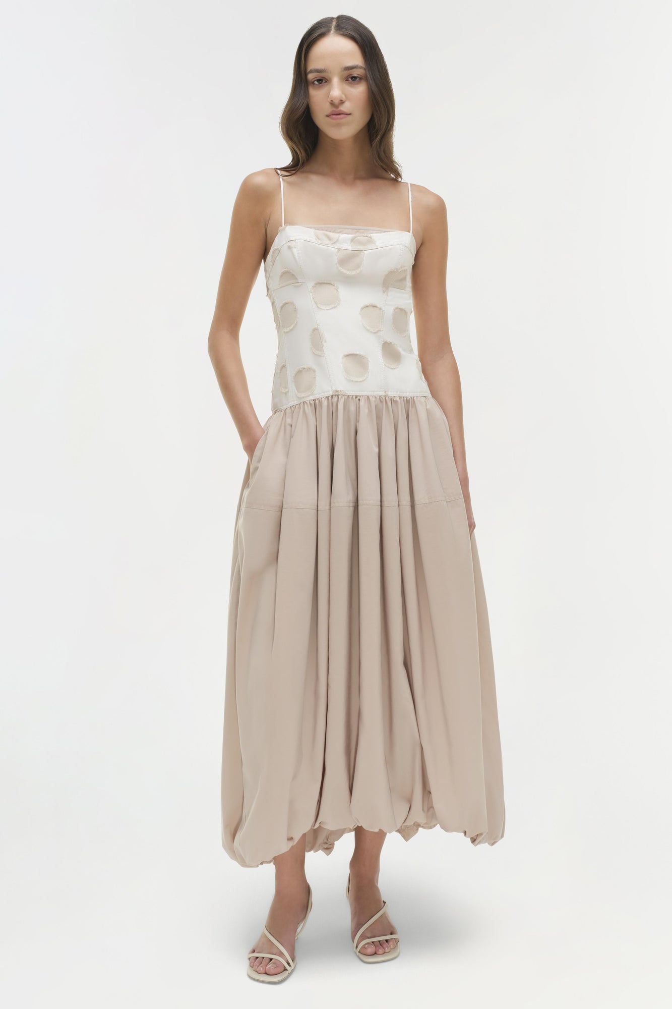 Sleeveless midi dress with cream polka dot top, beige pleated skirt, and thin straps.