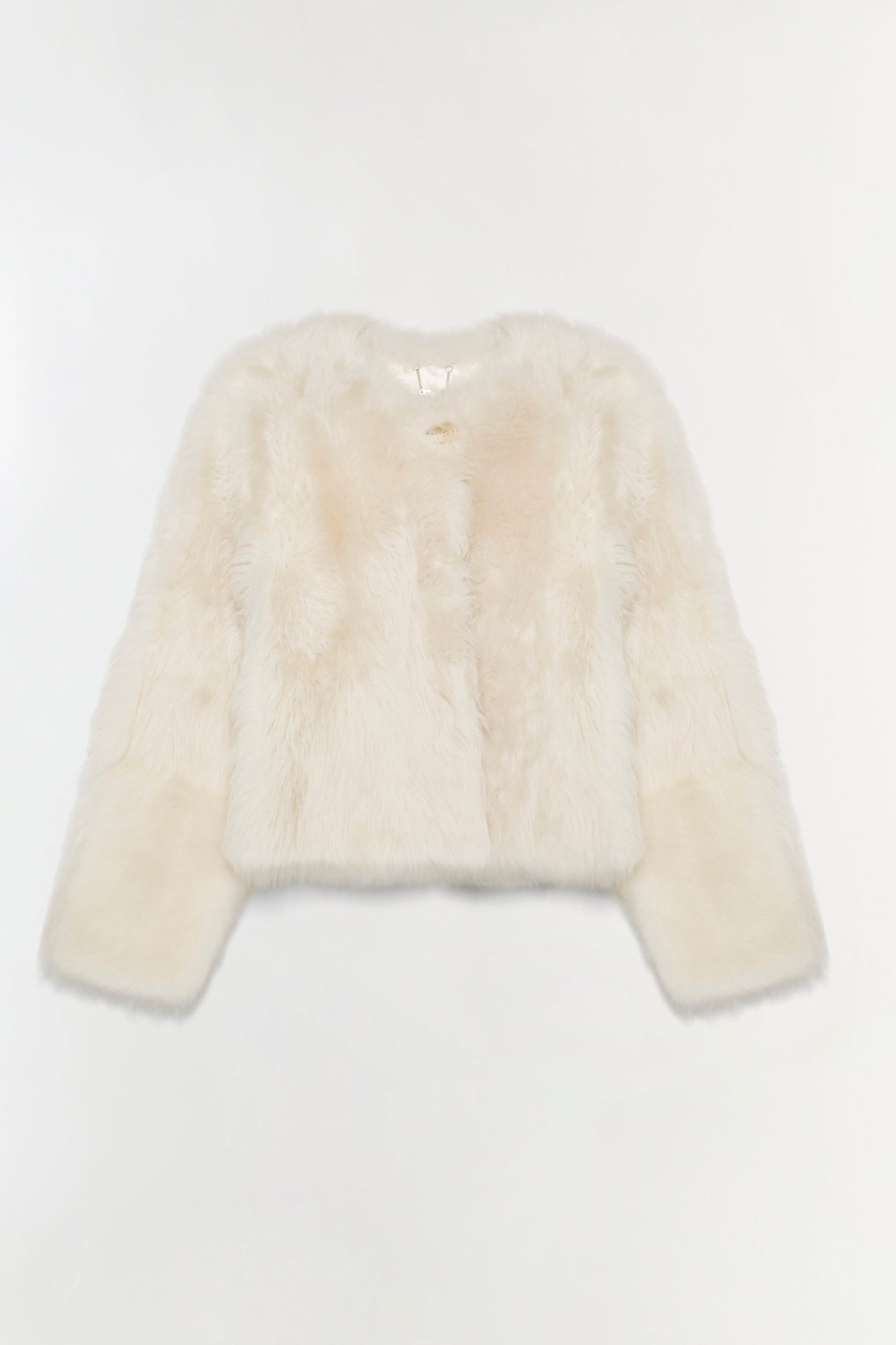 Cream-colored shearling jacket with long sleeves, cropped length, and single button closure at neckline.