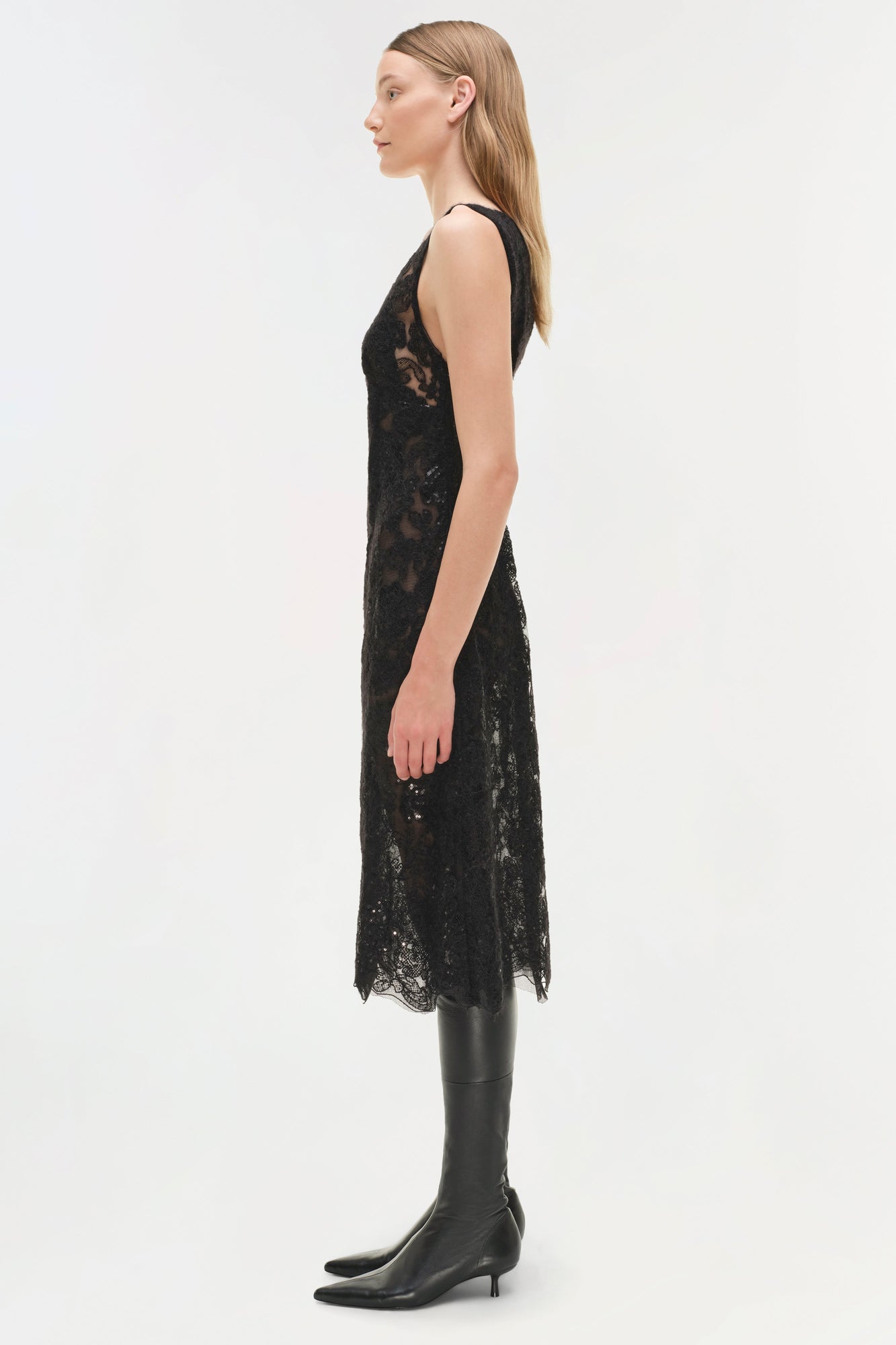 Black sequin lace sleeveless midi dress with open back, worn with black knee-high boots.