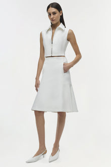 White sleeveless shirt dress with collar and front zip, brown belt detail, paired with white pointed kitten heels.