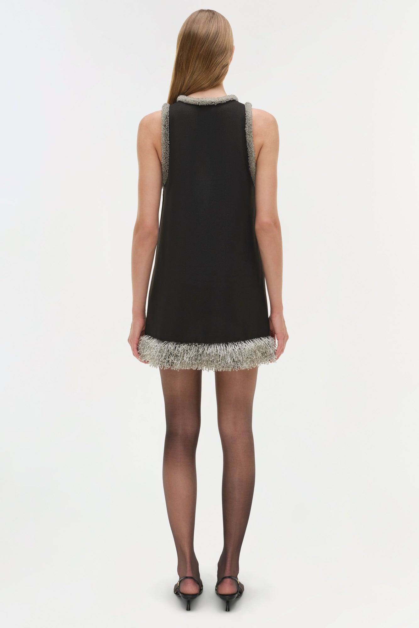 Black sleeveless mini dress with silver beaded trim at neckline and hem, shown from back.