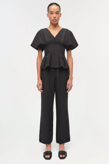 Woman wearing black cotton faille pull-on pants with cropped straight-leg fit and peplum top.