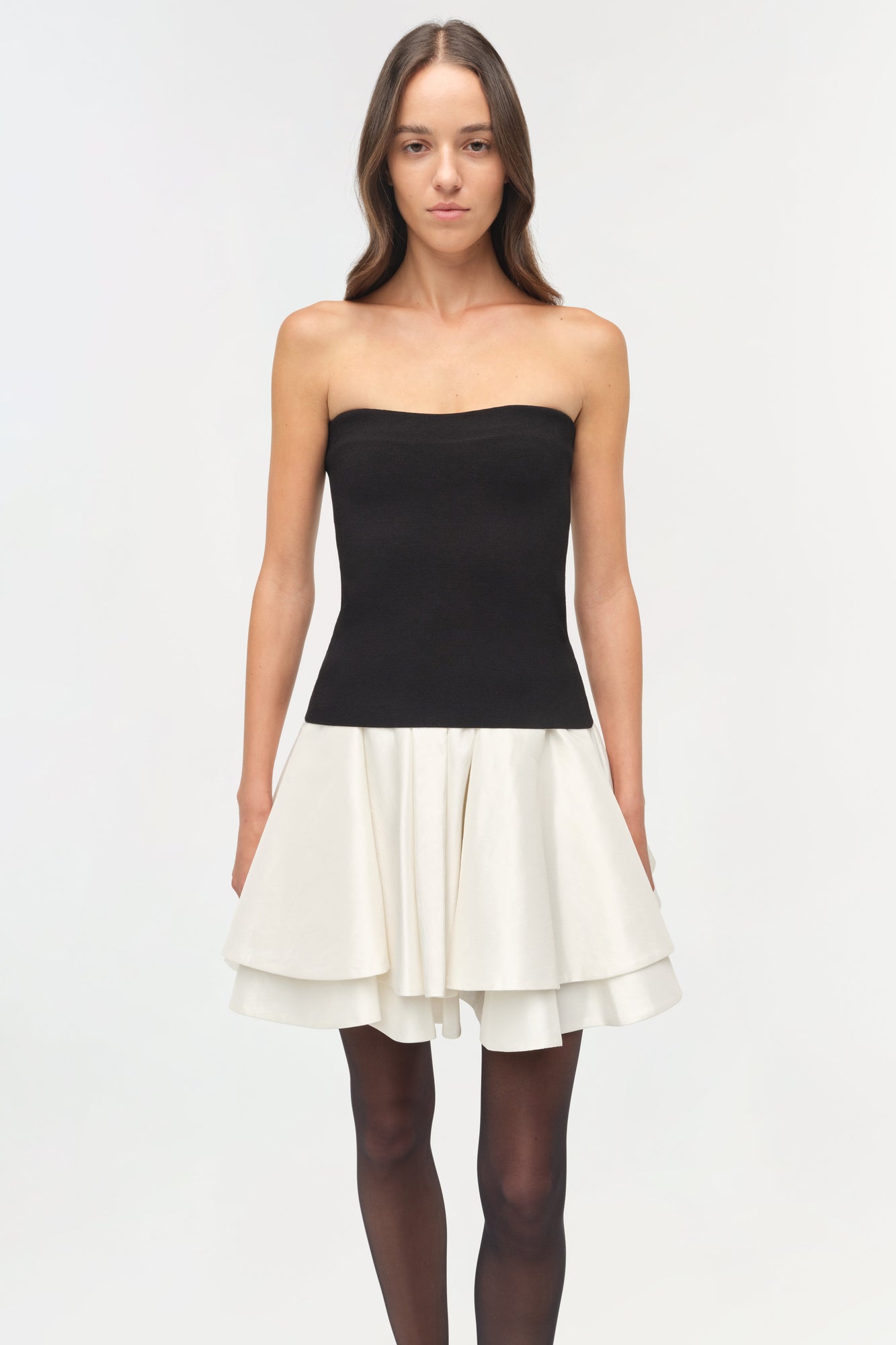 Black knit strapless top with white pleated taffeta skirt, modeled with dark tights.
