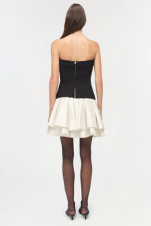 Black strapless knit bodice with cream tiered taffeta skirt, shown from back with dark tights and heels.