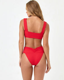 back view of woman wearing a red bikini against a white background