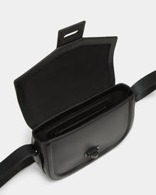 The Rudsak ALORA - 8324506 Black crossbody bag features premium leather, a wide adjustable strap, minimalist design, and an open flap revealing a spacious interior with an inner zippered pocket.