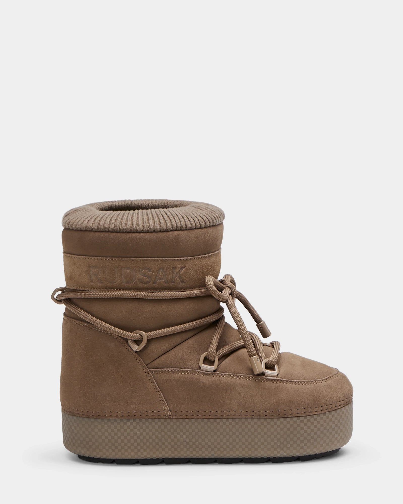 The Rudsak MACE S - 8224543 Camel is a tan suede women's short moon boot with thick ribbed ankle padding, faux fur lining, decorative crisscross laces, and a textured rubber sole. "RUDSAK" is embossed on the upper side.
