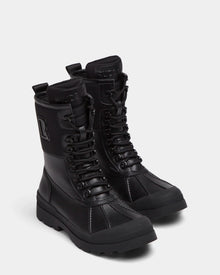 The Rudsak RITA - L222502 Black women's winter boots feature mid-calf lace-up design, weather-treated leather, rugged soles, and embossed branding on the tongue and side, shown on a plain light background.