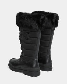The Rudsak WINDY - L224507 Black is a pair of tall women’s winter boots featuring faux fur trim, quilted sides, thick rubber soles, decorative laces, a side zipper, and an 