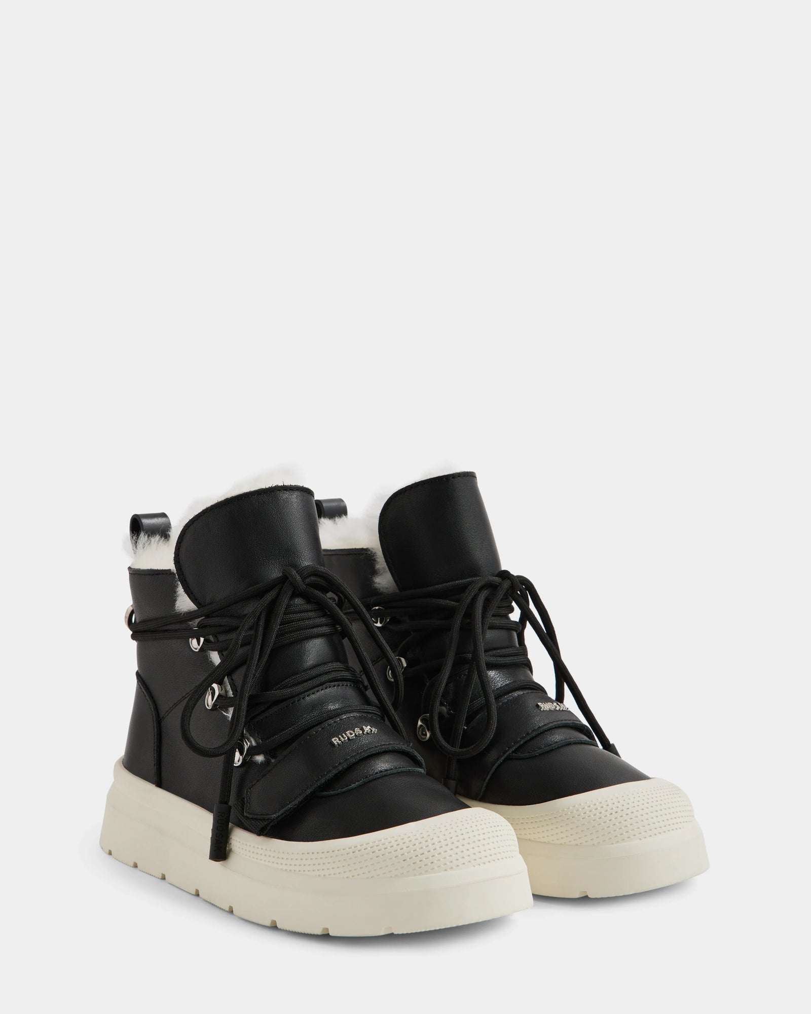 Rudsak’s ALEXEY L - L225518 Black high-top sneakers feature cozy wool lining, thick white rubber soles, black laces, and silver eyelets—a stylish winter boot photographed on a light gray background.