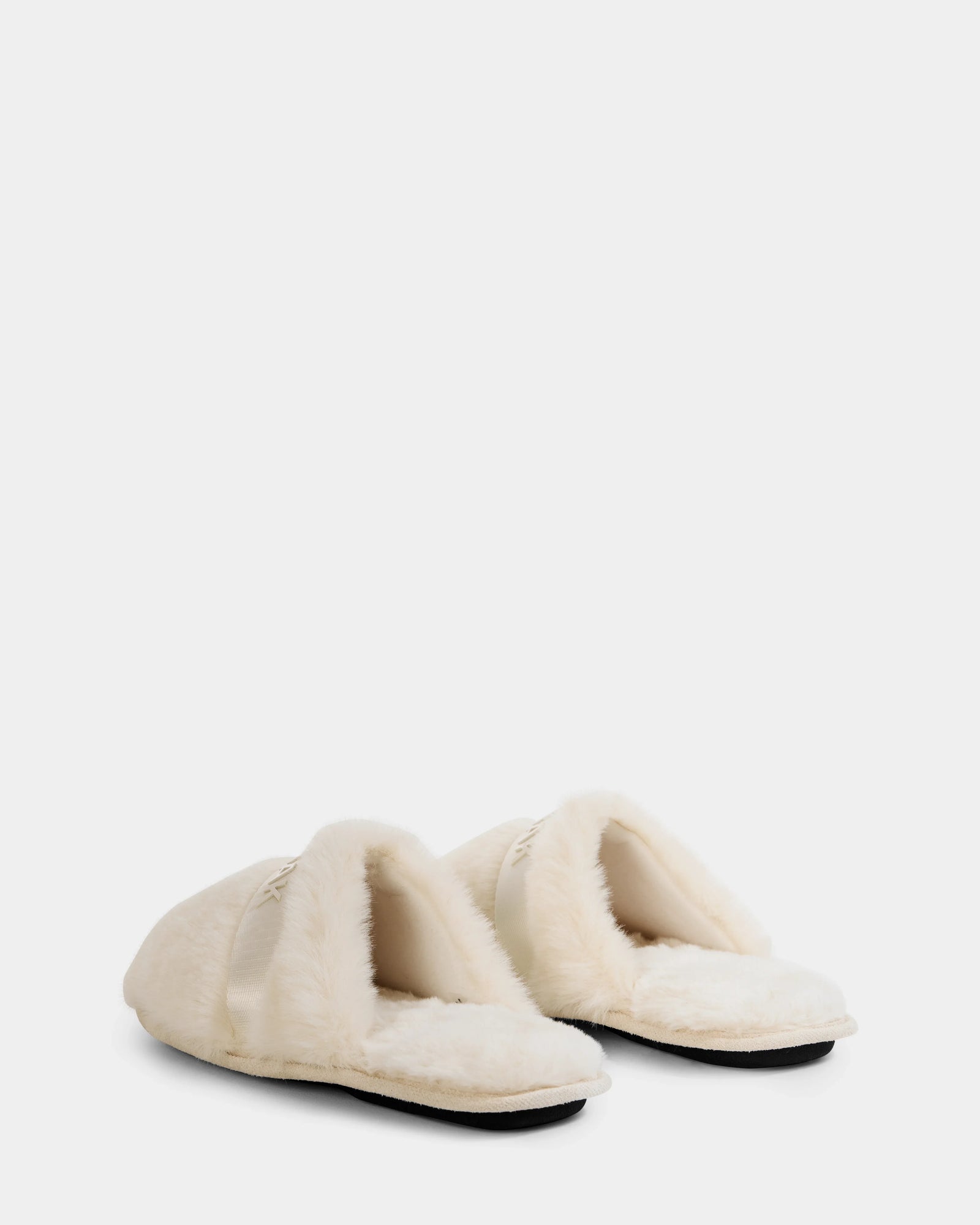 The FLUFF - L223509 Cream women’s faux-fur slippers by Rudsak feature cozy cream plush, open backs, and flat soles with non-slip traction—designed for ultimate comfort. Shown against a plain white background.