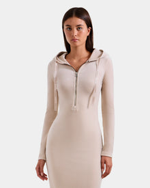 A young woman wears the Rudsak ISABELLA - L525502 Cream fitted long-sleeve velour hooded midi dress with front zipper and drawstrings, standing against a plain white background.