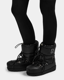 A person wears black leggings and Rudsak KIKA - L224506 Black women's winter boots, featuring chunky rubber soles, laces, an 