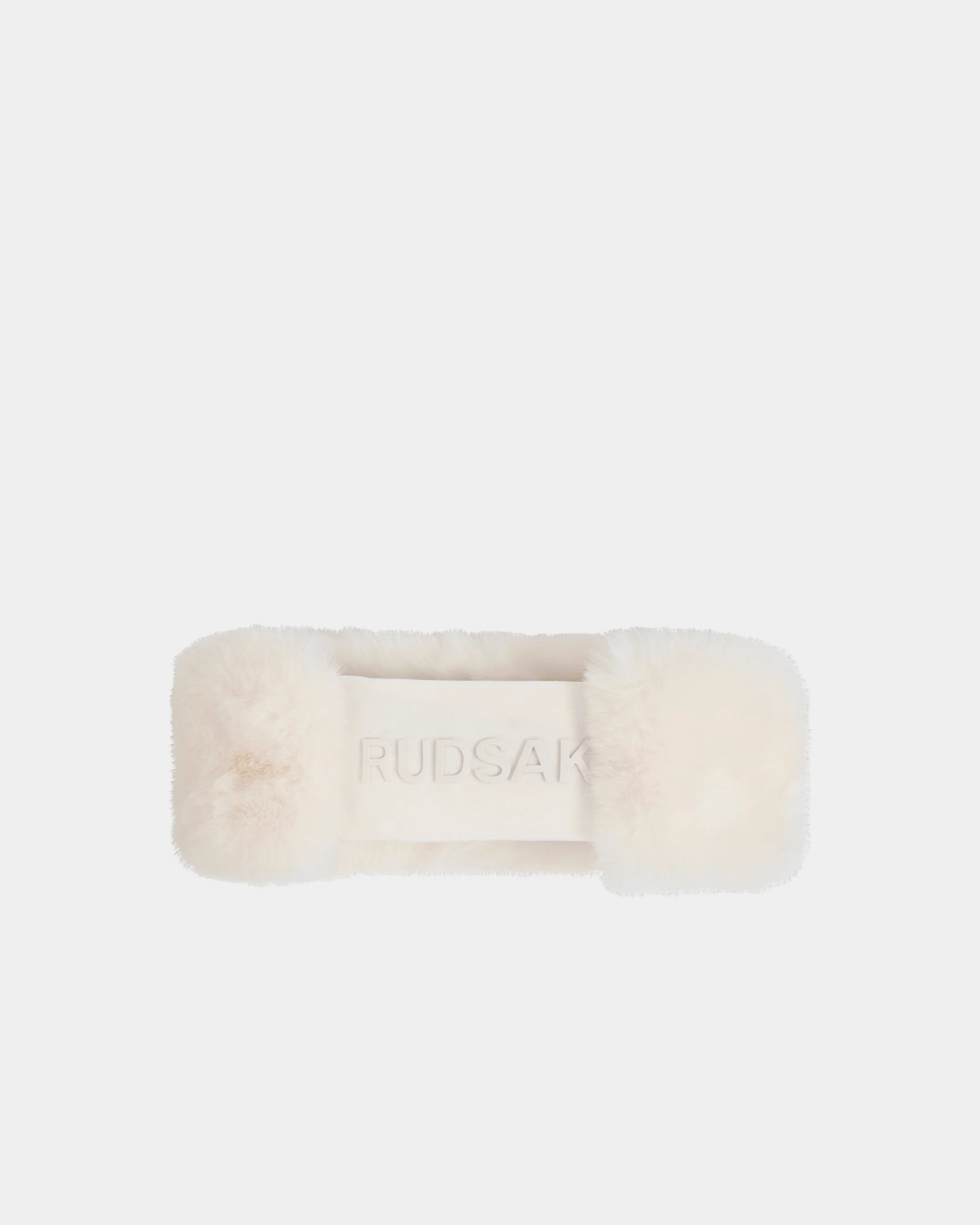 The SANDIE - L425552 Iceland by Rudsak is a cream-colored rectangular faux fur women’s headband with RUDSAK embossed in the center, shown on a plain white background—an elegant winter accessory.