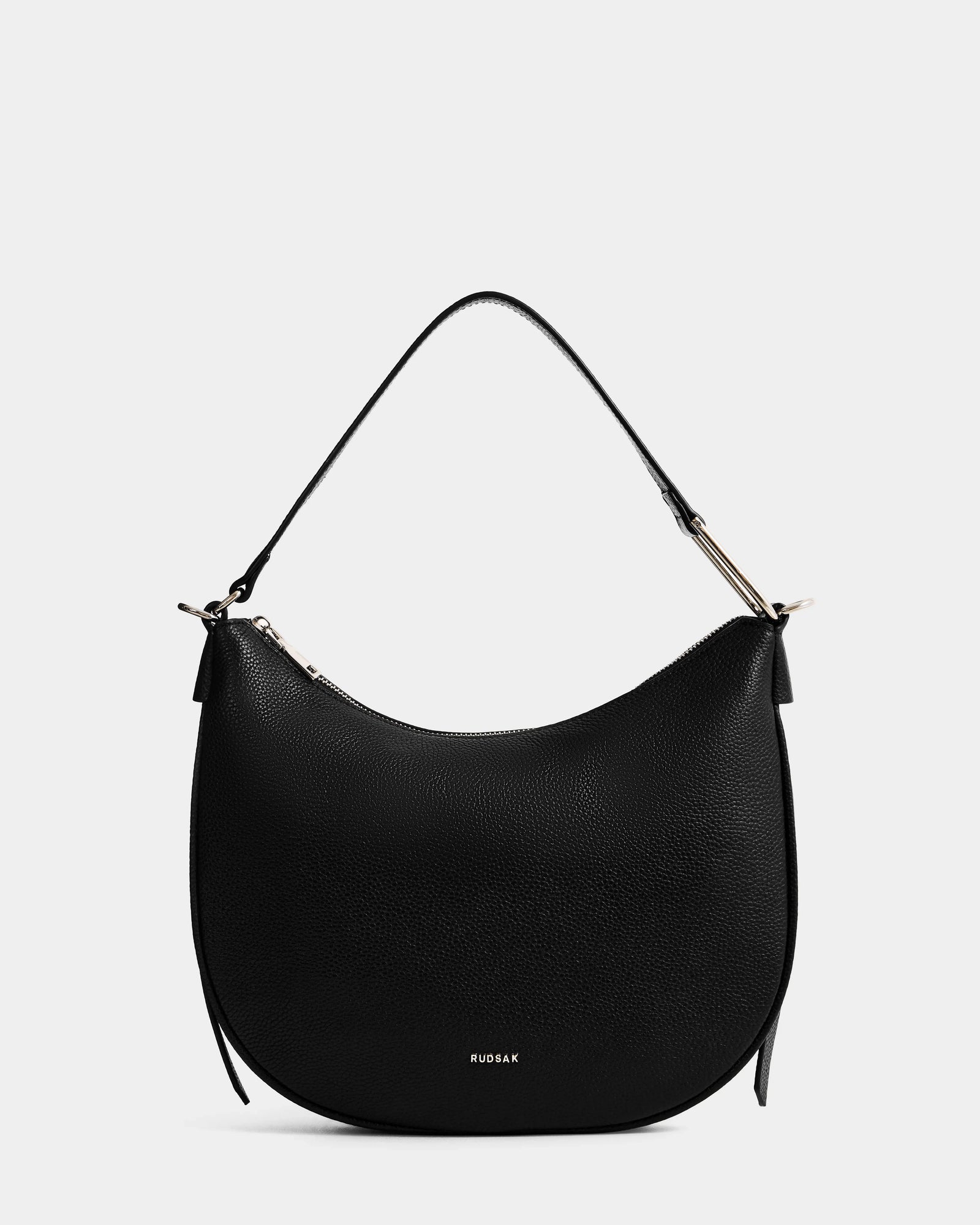The Rudsak SYLVIA - L325515 Black is a chic women’s hobo shoulder bag, crafted in black leather with a crescent silhouette, single strap, gold-tone hardware, and the HUGS&K logo in gold at the bottom. Shown on a plain white background.