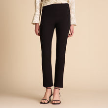 Person wearing black pants and a patterned top on a beige background | Lead