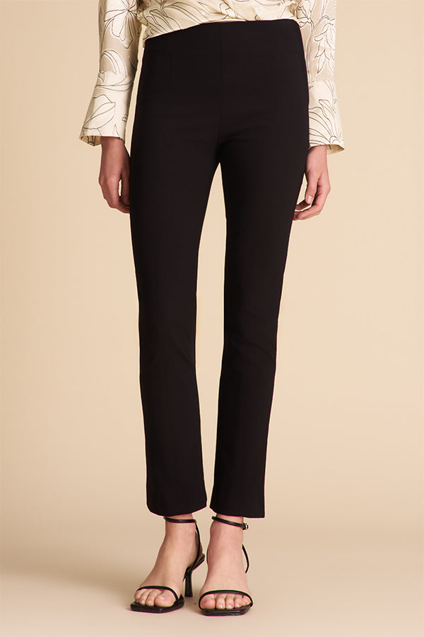 Person wearing black pants and a patterned top on a beige background | Exclude | Grid