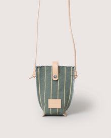 A small green Graf Lantz Hana Canvas Phone Crossbody features vertical yellow stripes, a beige leather snap closure, matching strap, and a rectangular beige leather logo patch on the front, shown against a light background.