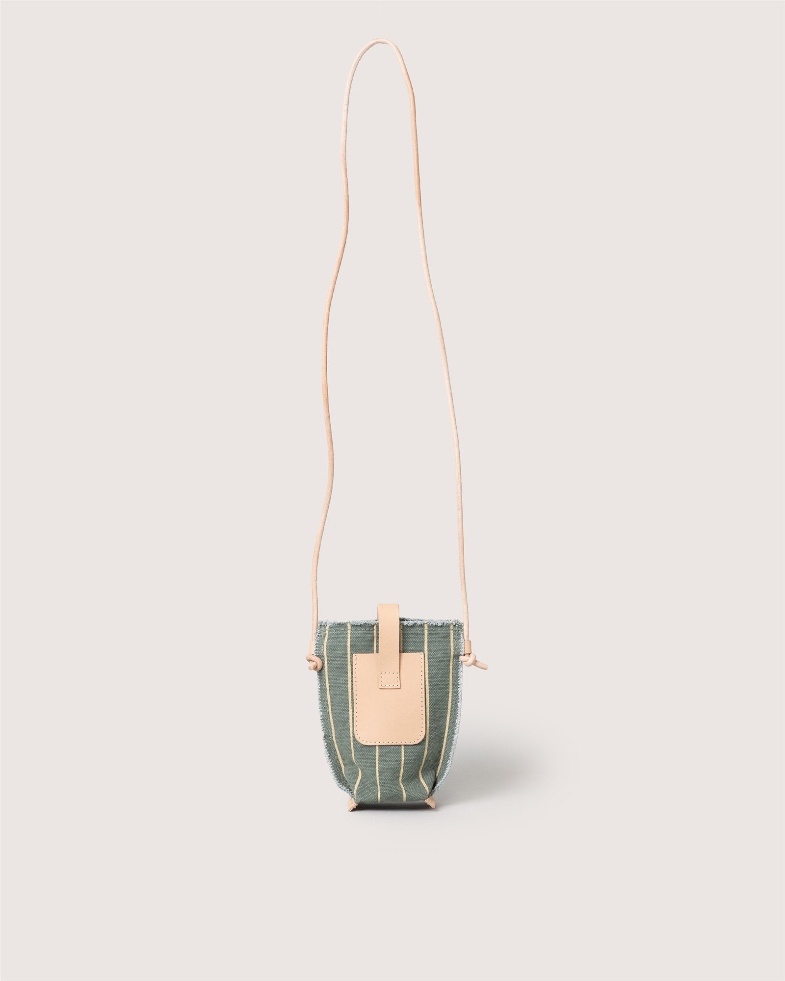 The Graf Lantz Hana Canvas Phone Crossbody is a compact green fabric bag with vertical beige stripes, a tan leather flap closure, and a long tan strap, shown against a light neutral background.