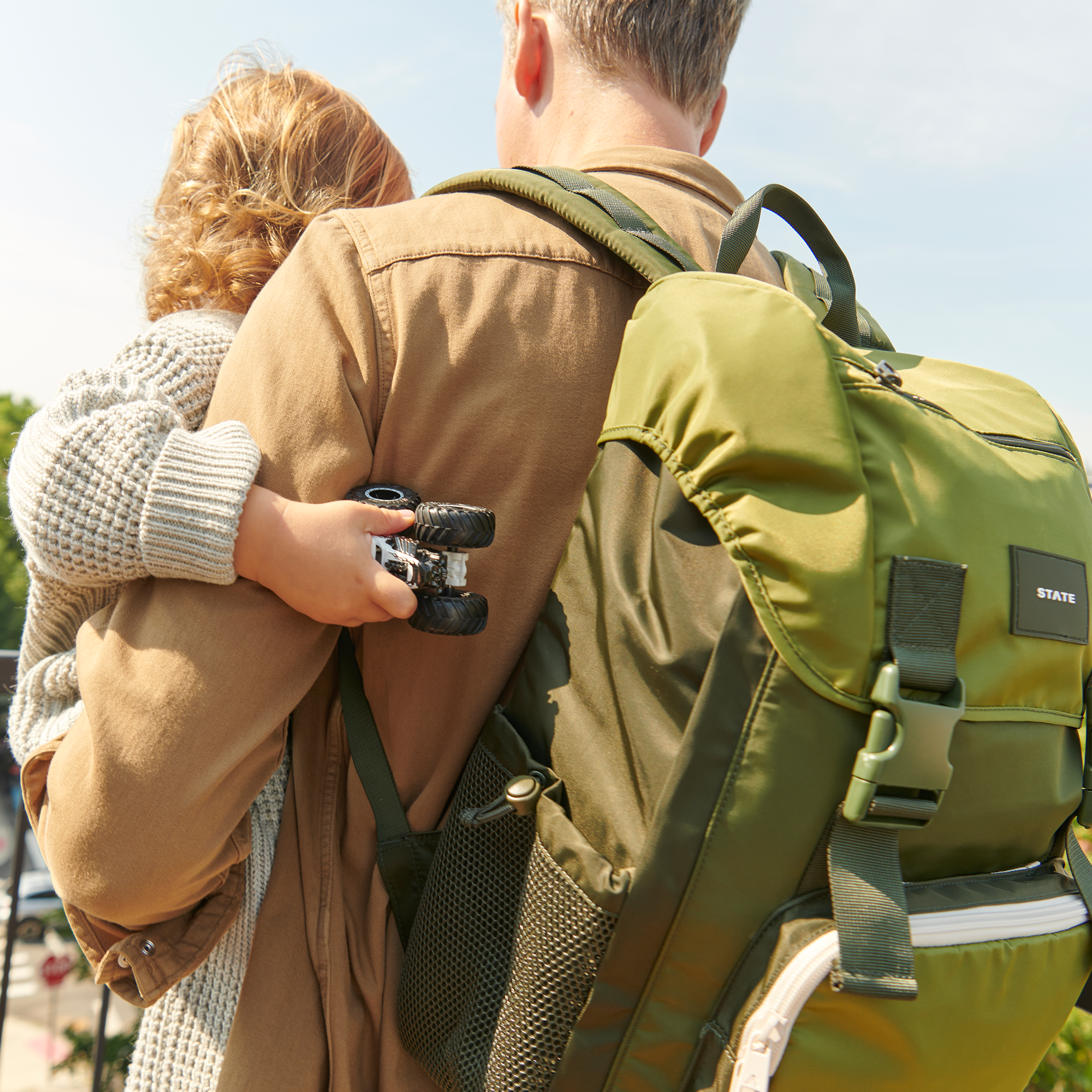 Dad wearing Grove Rucksack Olive while holding baby