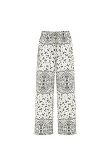 Cream and black wide leg pants with bandana print and decorative lace panel details throughout.