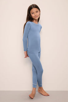 Model wears Kids TENCEL Modal Unisex Long PJ Set in Wedgewood Blue/Ivory.