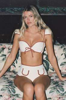 Cream bikini top with terracotta bow ties at center front and shoulder straps.