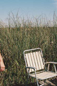 Oat and terracotta bikini bottom with bound edges, displayed on model in marshland setting.