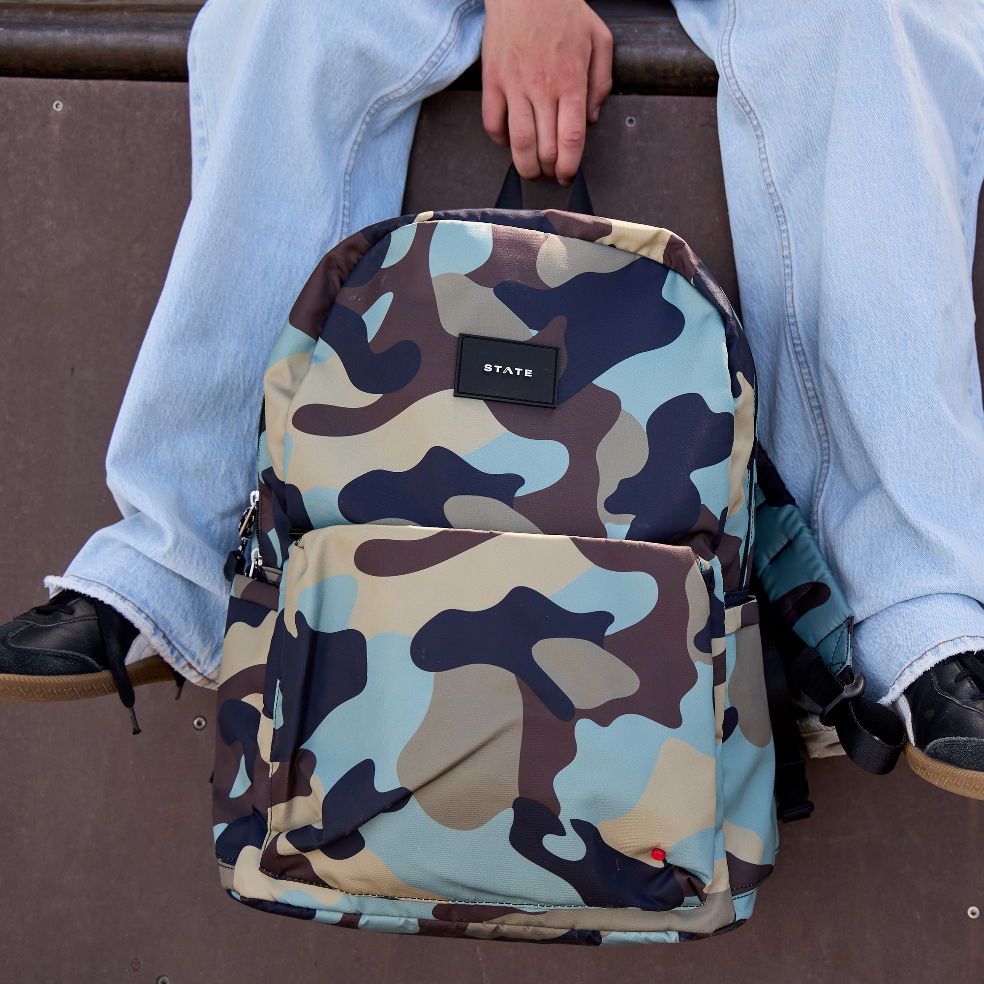 boy holding camo backpack between his legs