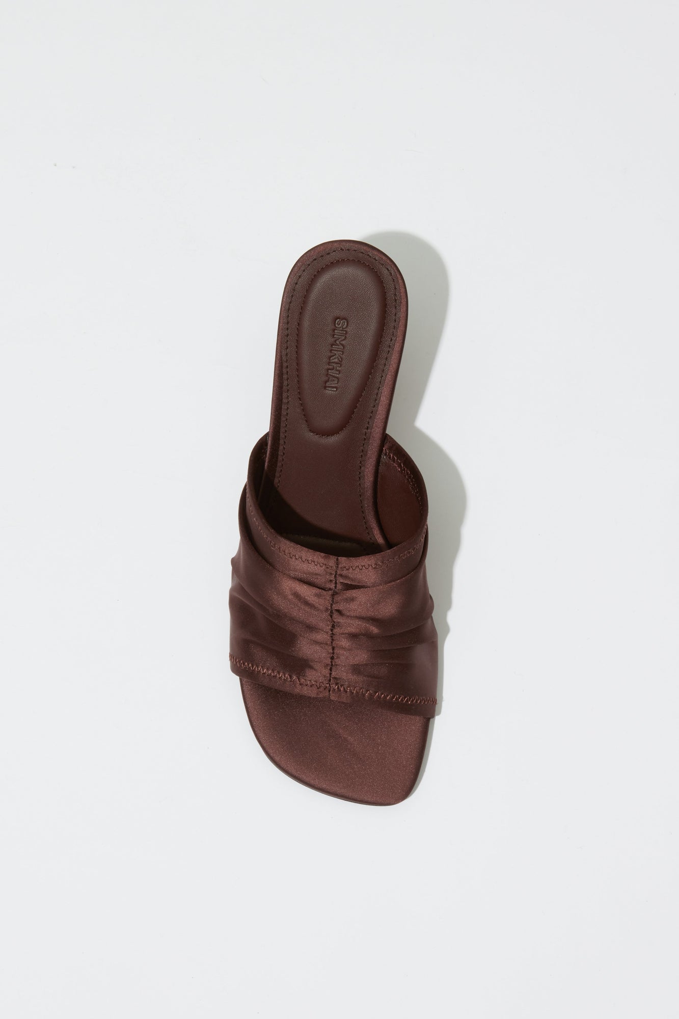 Dark brown satin mule with padded upper strap and square toe, shown from above.