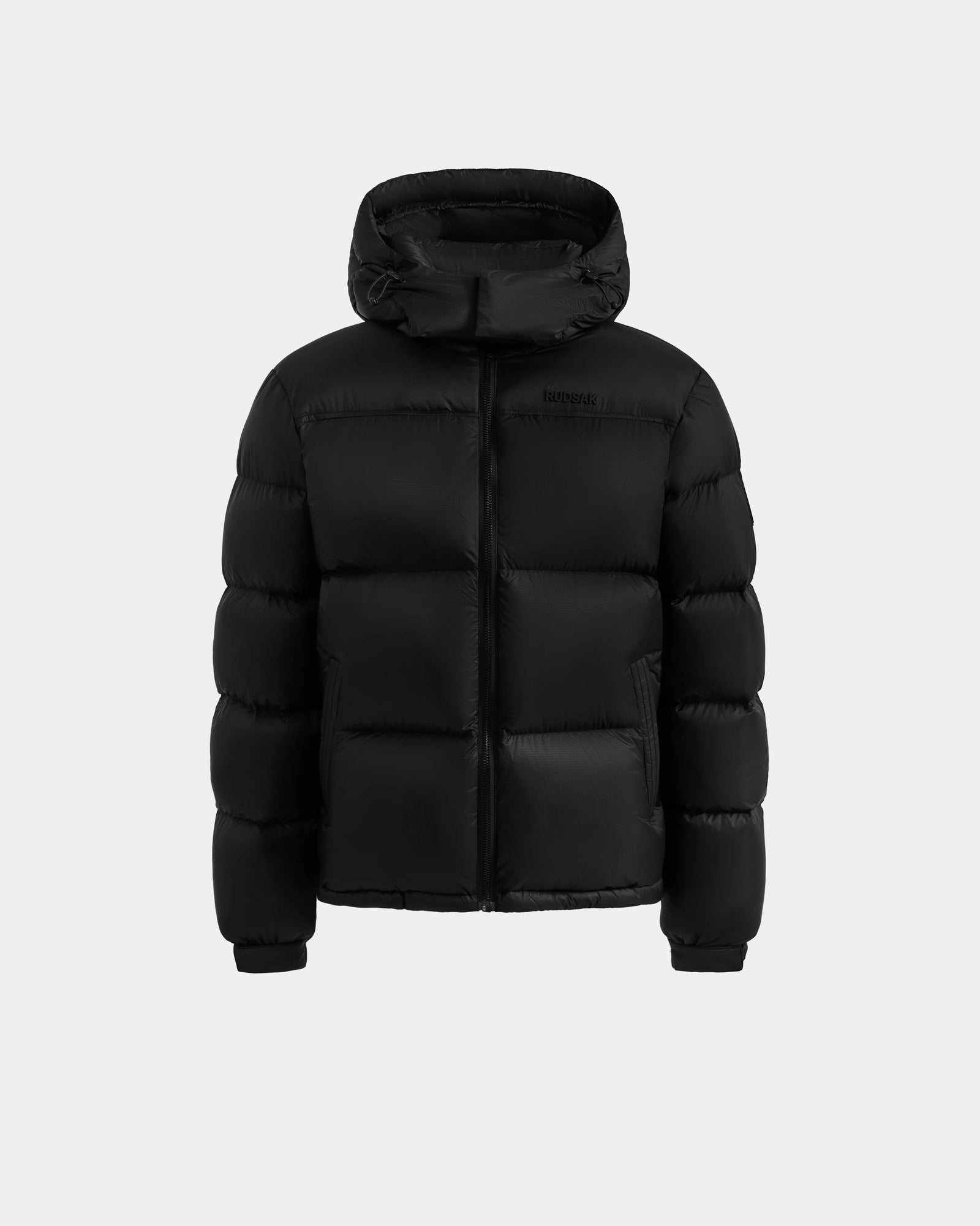 The Rudsak STEFANO - 6125574 Black men’s quilted down puffer jacket features a hood, front zipper, and insulated sections. Displayed on a light gray background, it’s ideal winter outerwear with RDS-certified down for superior warmth.