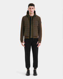 A man faces forward against a white background, wearing the Rudsak DEE MAT - 6124028 Army lightweight hybrid down jacket over a zip-up top, with black jogger pants and black sneakers.