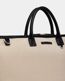 A close-up of the Rudsak DUBLIN - 9324514 Vanilla tote, a beige canvas leather weekender with black handles and silver hardware, set against a plain light gray background.