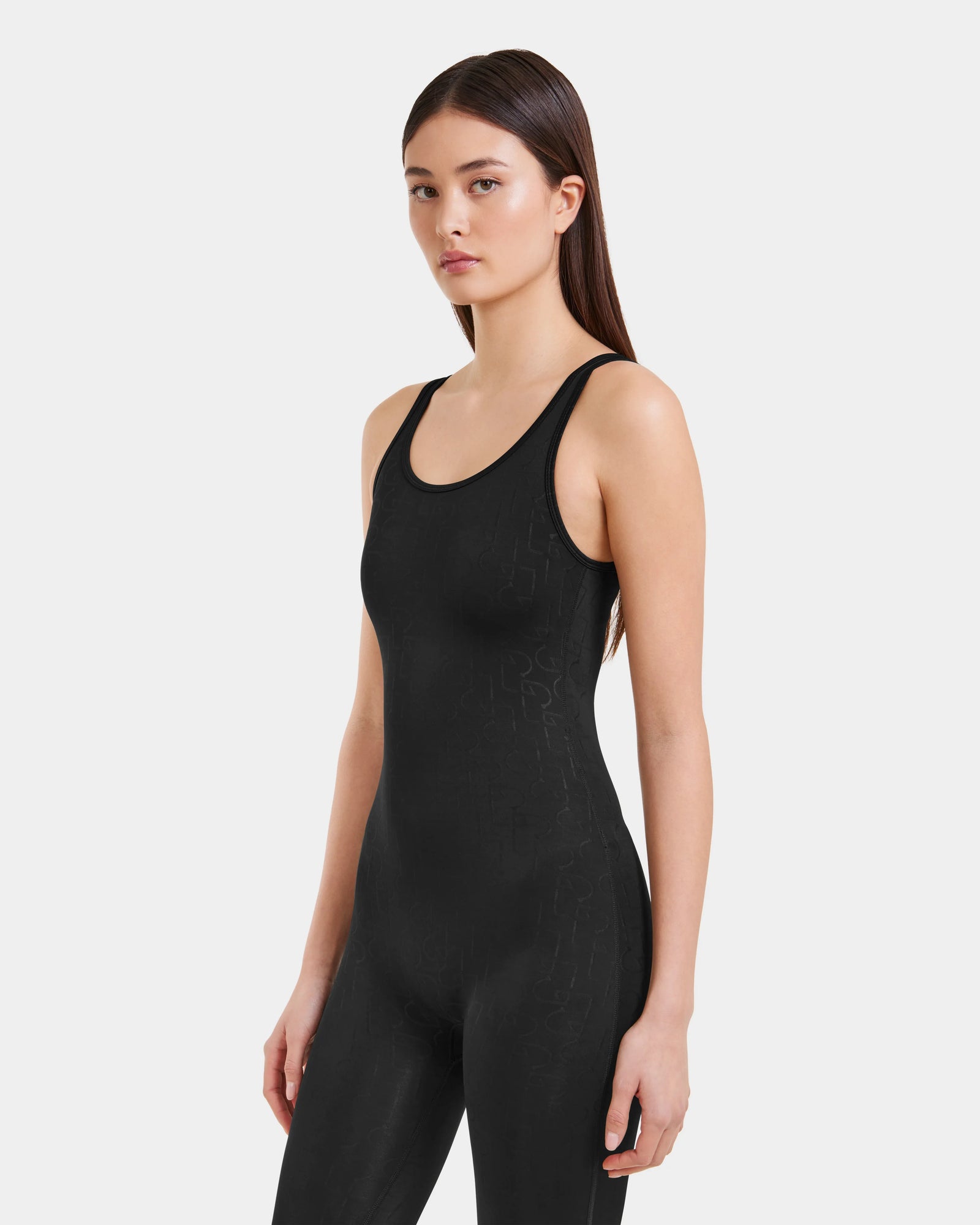 A young woman with straight, long dark hair wears the LAWREN - 8523054 Rudsak Pattern bodysuit by Rudsak. She stands against a plain light background, facing slightly to the side with a neutral expression.