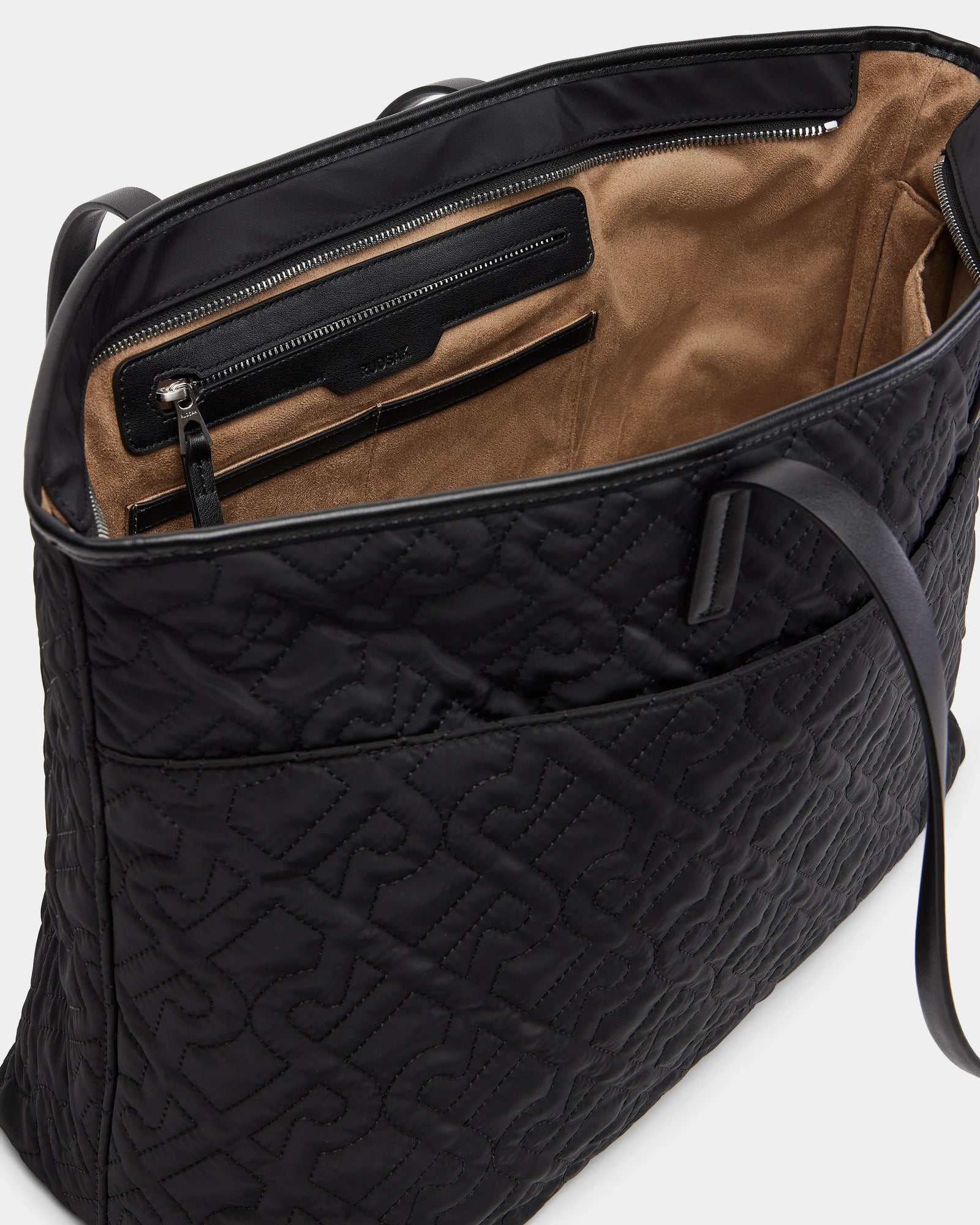 The LIVORNO - L325007 Black by Rudsak is a black quilted monogram tote with large embossed letters, brown suede lining, a spacious interior, a zippered pocket, and slip pockets—a luxurious carryall.
