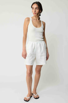 Woman wearing white linen shorts and a white tank top
