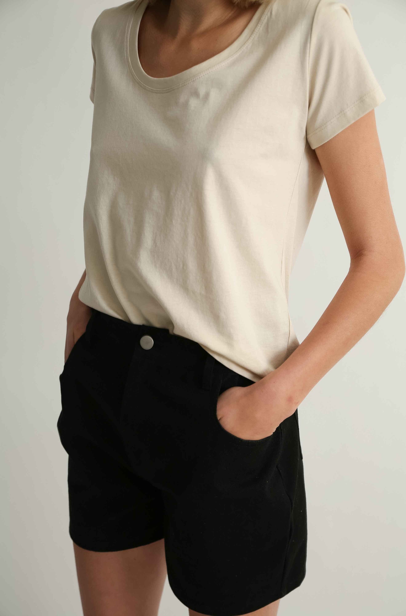 Woman wearing a beige tee and black shorts