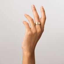 Model Close-up of a woman's hand with fingers gently curled upward, wearing a wide gold ring with an engraved floral design