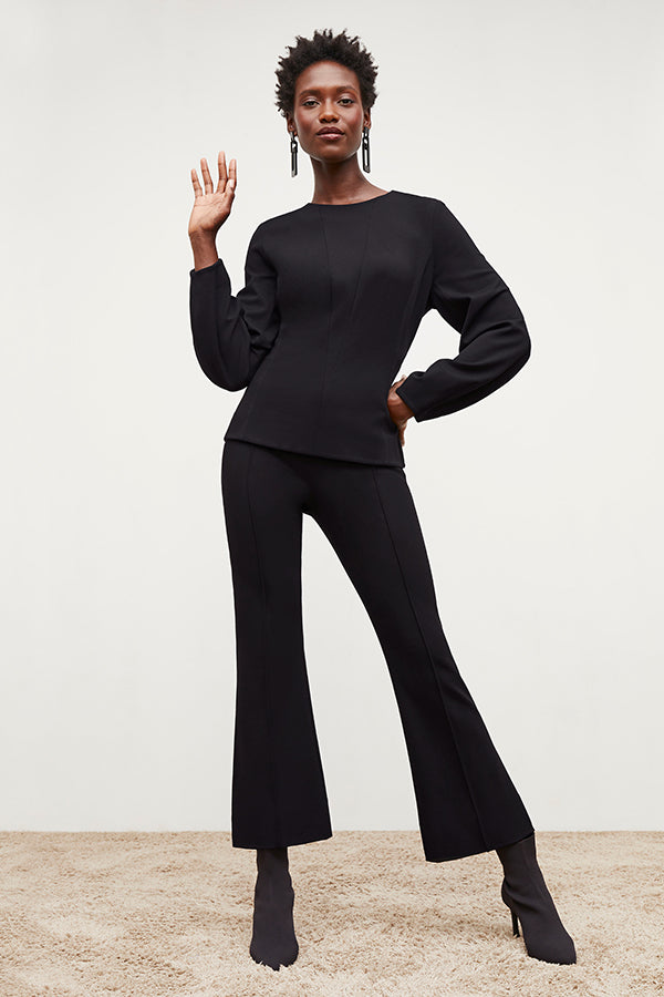 Front image of a woman standing wearing the rashida top in black | Exclude